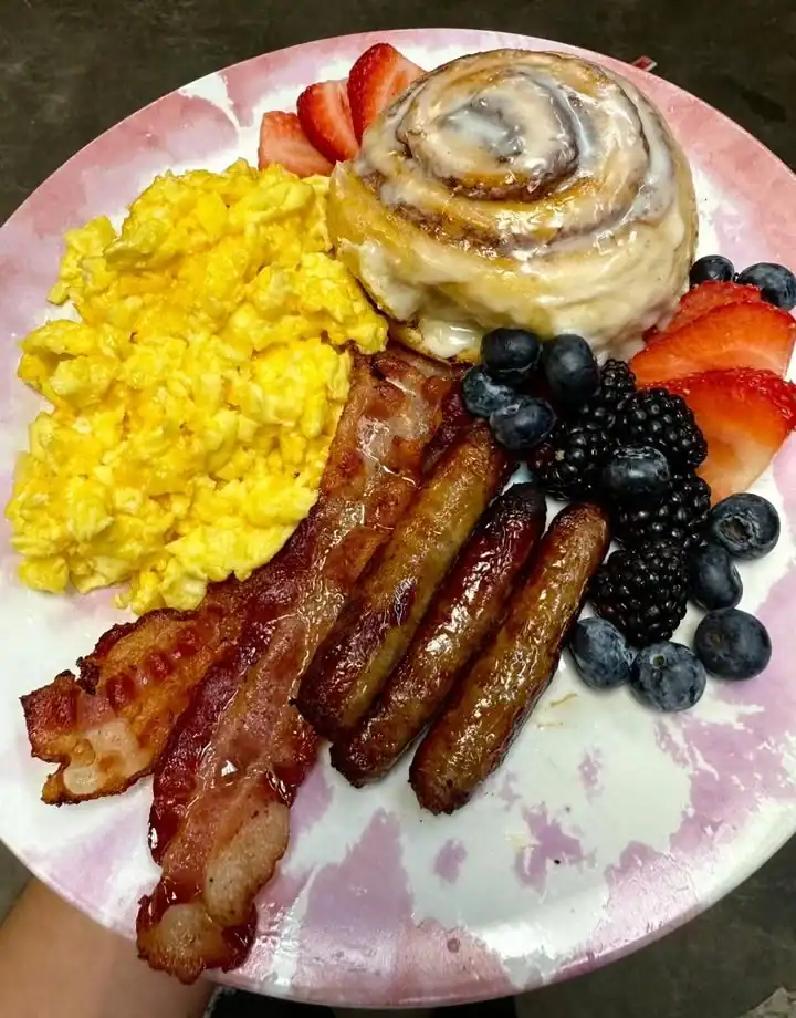 A hearty Big Breakfast with eggs, bacon, toast, and fresh fruit on a plate