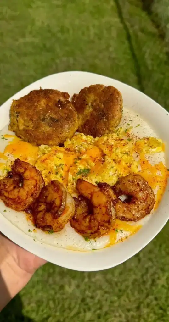 Plate of salmon patties with shrimp, cheesy eggs, and grits