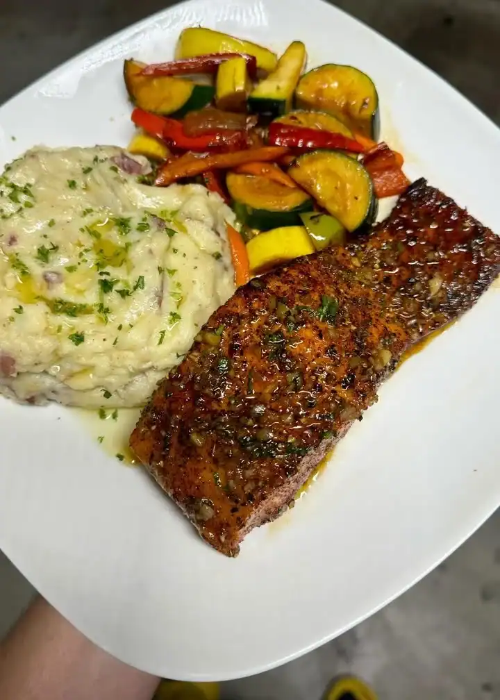 Delicious salmon fillet served with creamy mash and mixed vegetables on a plate.