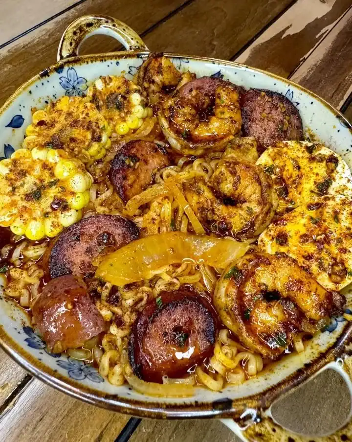 Bowl of Sausage & Shrimp Boil Ramen topped with herbs and spices
