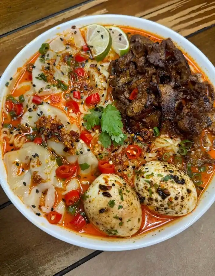 Bowl of spicy miso steak dumplings, garnished with green onions and chili flakes