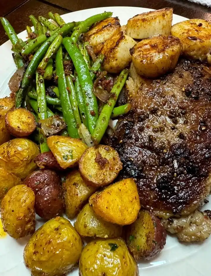 Beautifully plated Steak and Scallops dinner on a stylish dining table.