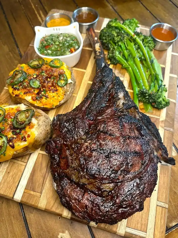 Tomahawk steak served with cheesy jalapeno bacon baked potatoes